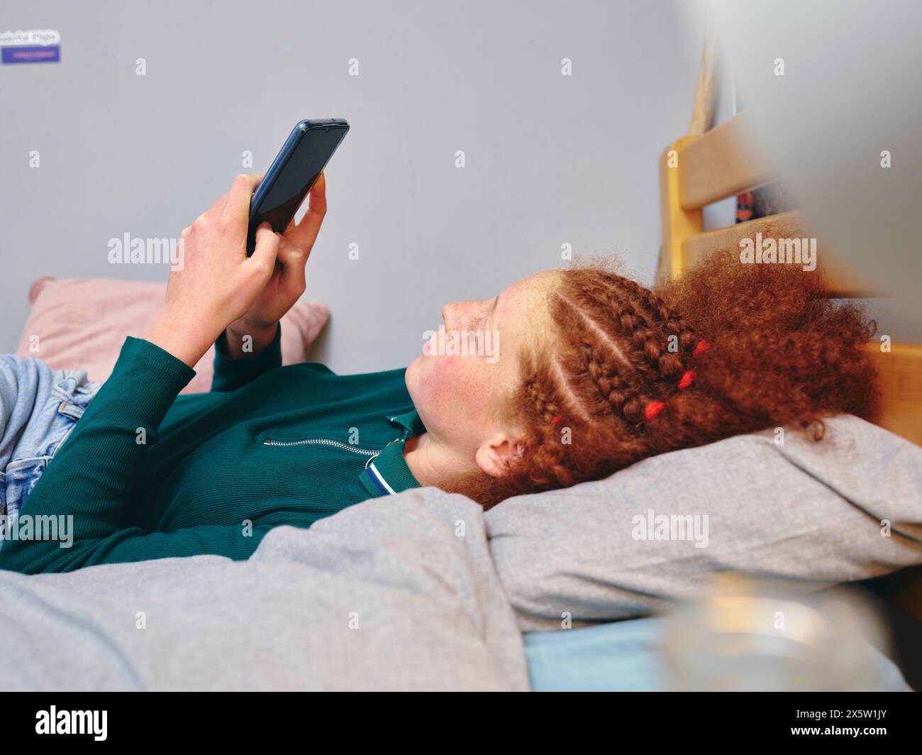 Girl lying on bed and using smart phone Stock Photo