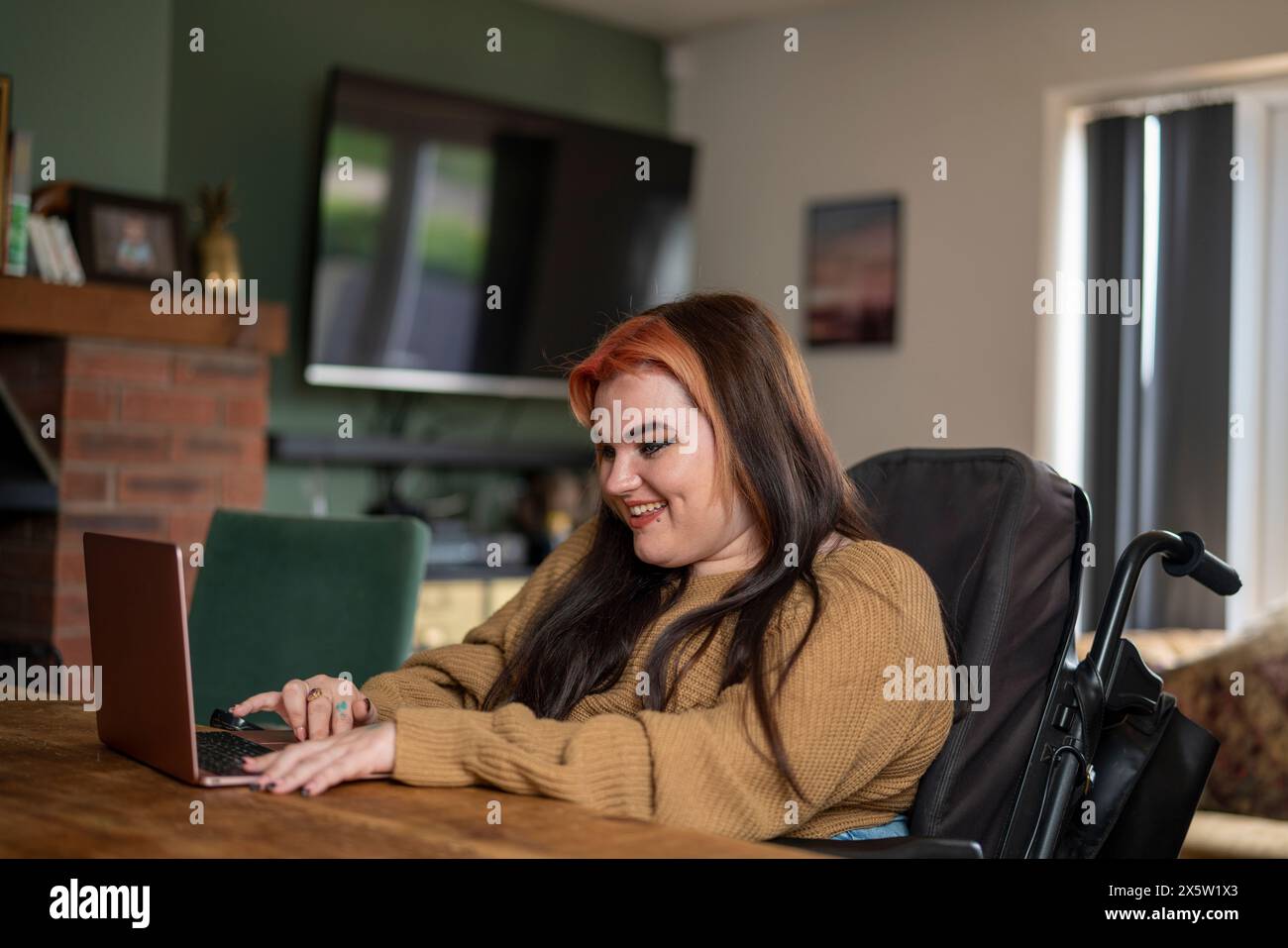 Woman in wheelchair working on laptop at home Stock Photo - Alamy