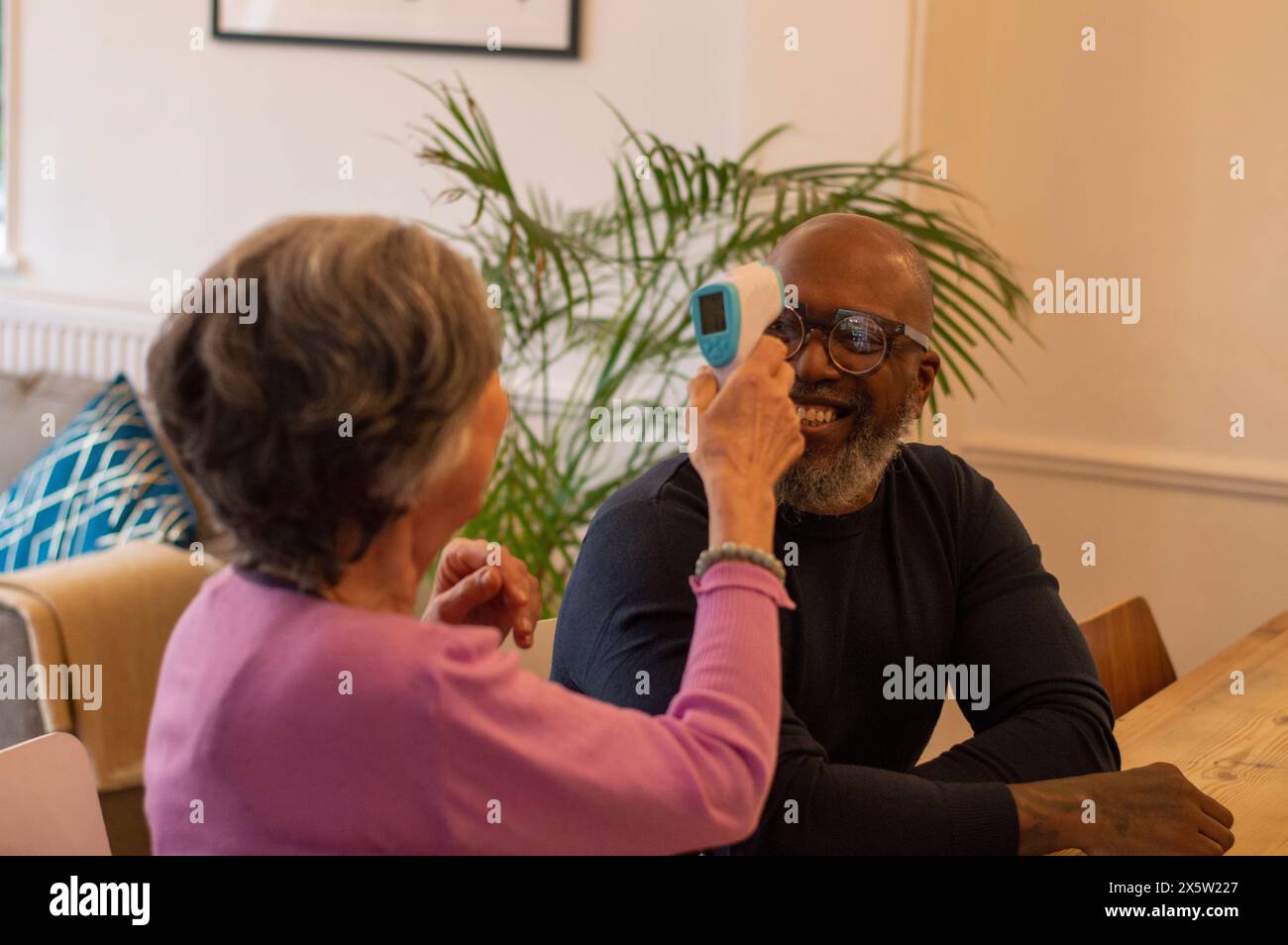 Woman measuring mans temperature at home Stock Photo