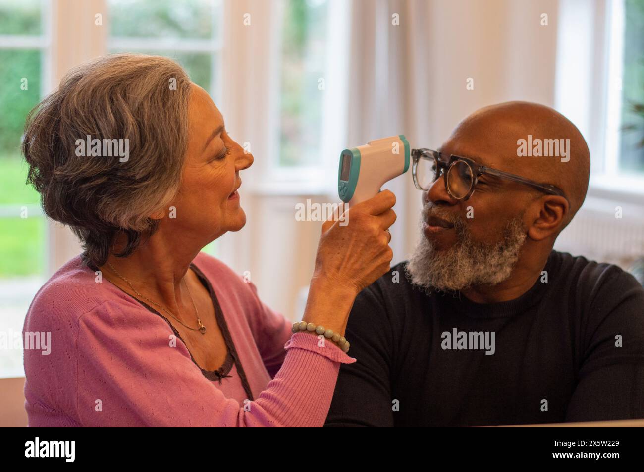 Woman measuring mans temperature at home Stock Photo