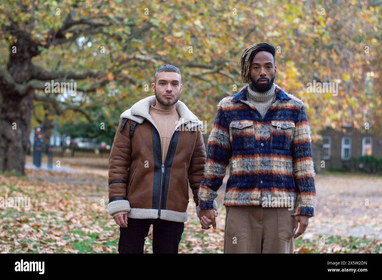 Mid adult men holding hands in park Stock Photo