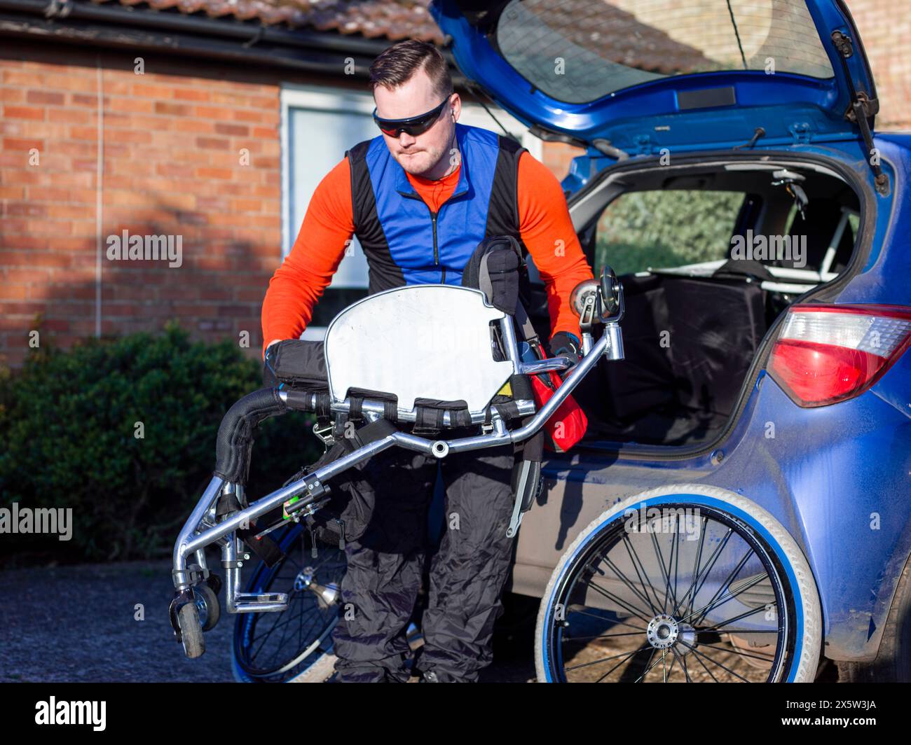 Disabled man setting up handcycle at car Stock Photo
