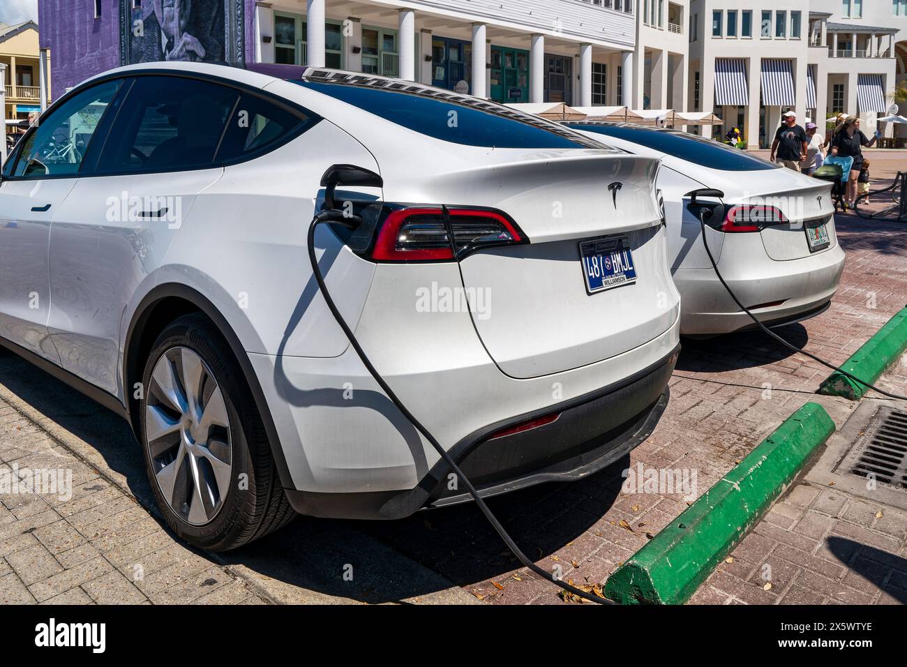 Tesla Model Y and Tesla Model 3 parked and charging at an electric vehicle or electric car charging station in a parking lot in Seaside Florida, USA. Stock Photo
