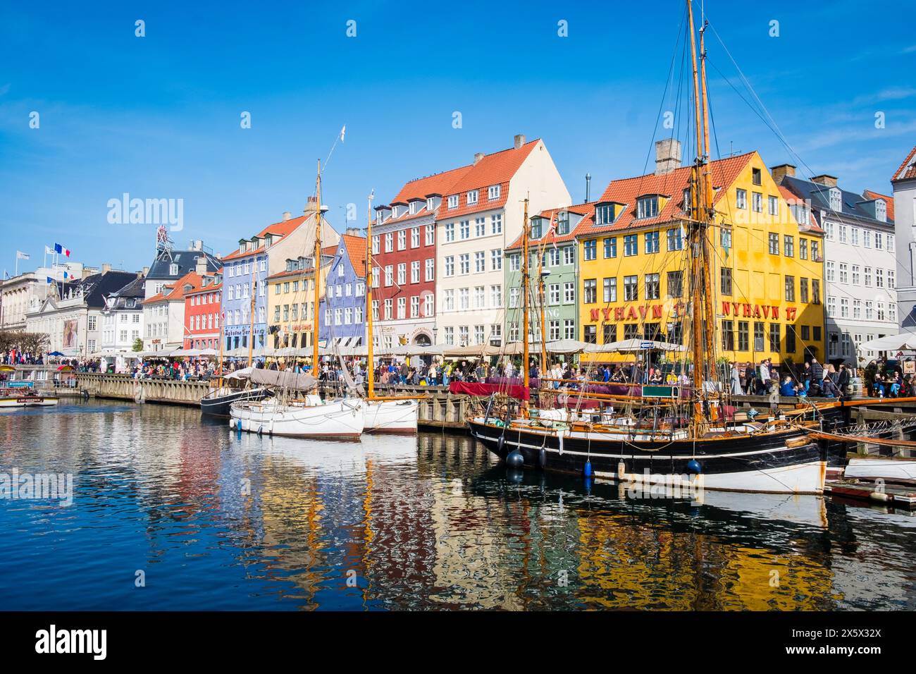 Copenhagen, Denmark - April 6, 2024: Crowded Nyhavn waterfront, canal and entertainment district in Copenhagen lined by brightly coloured historic tow Stock Photo