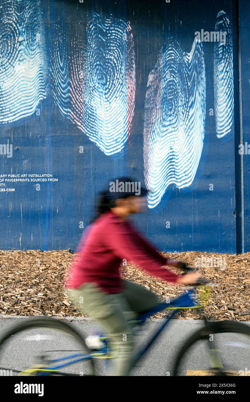 Woman cyclist riding past an urban art installation in Calgary, Alberta Canada Stock Photo