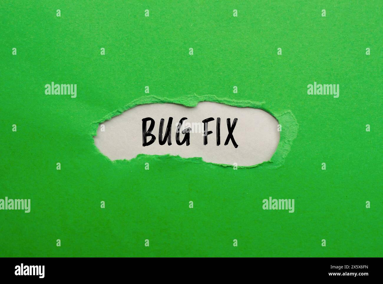 Bug fix words written on ripped green paper with gray background ...