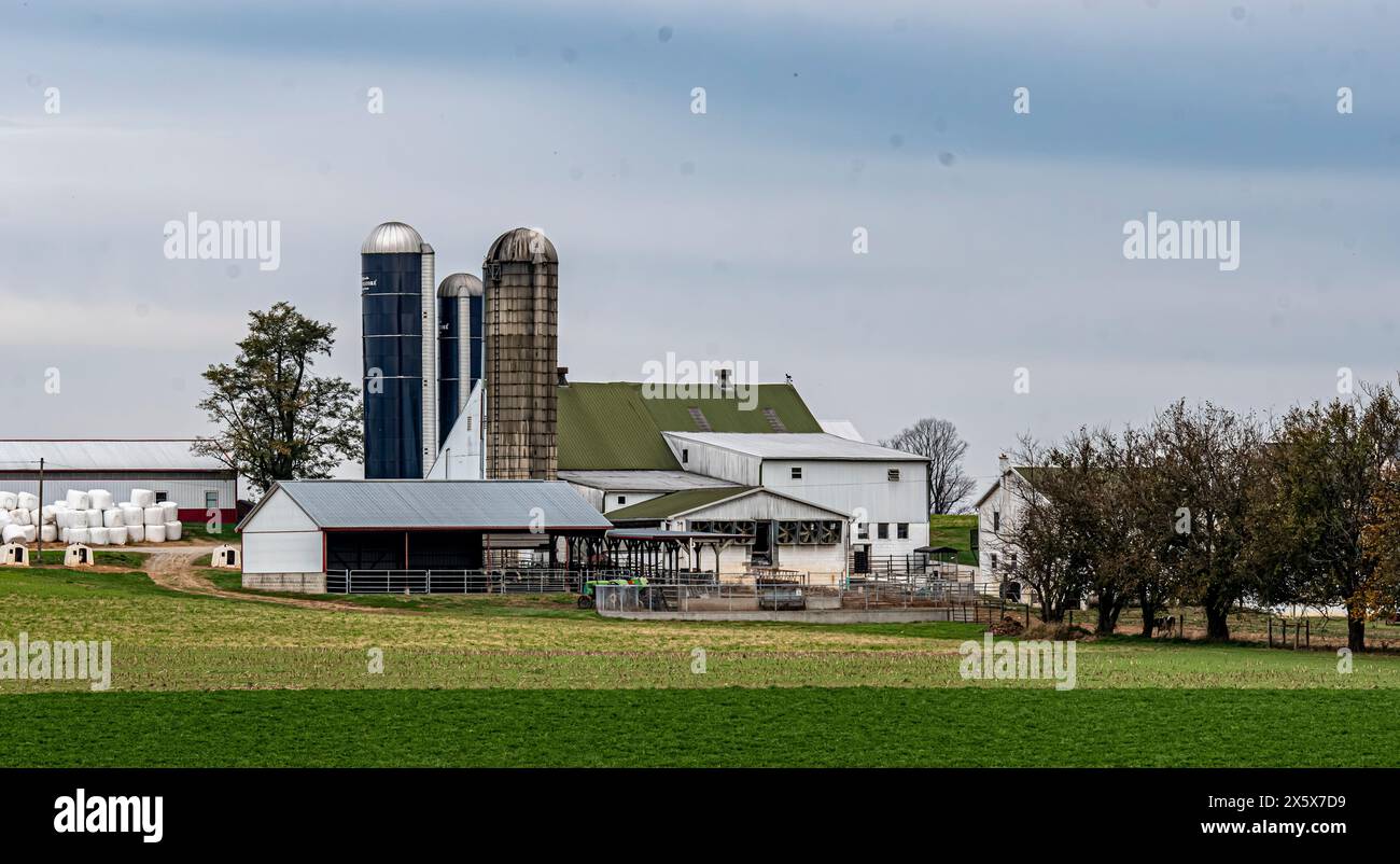 A detailed view of a modern dairy farm, featuring large silos and ...