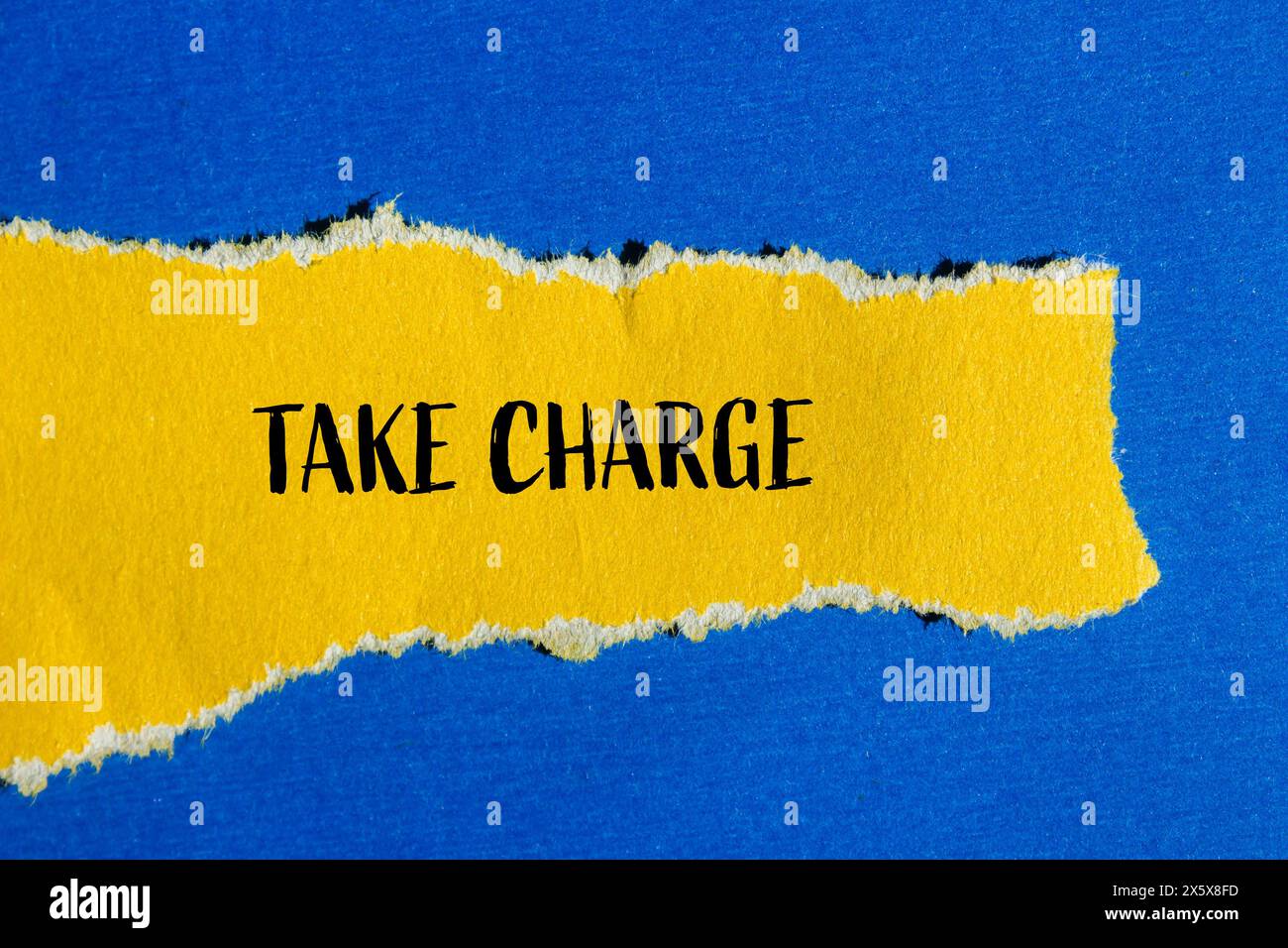 Take charge words written on ripped yellow paper with blue background. Conceptual take charge symbol. Copy space. Stock Photo