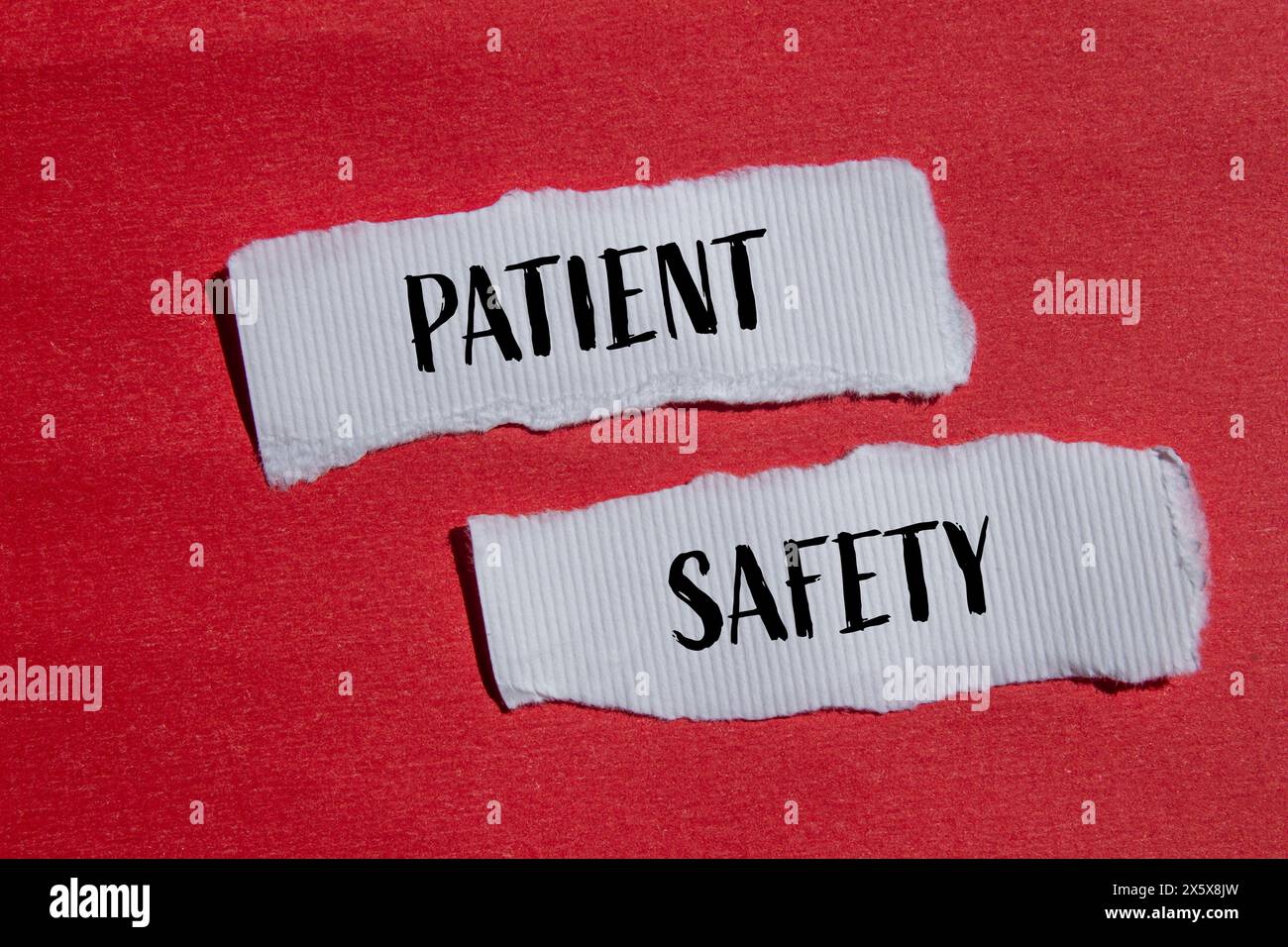 Patient safety words written on ripped white paper pieces with red background. Conceptual patient safety symbol. Copy space. Stock Photo