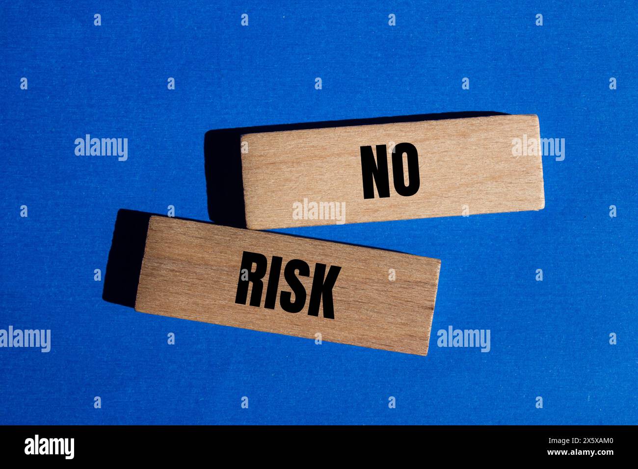 No risk words written on wooden blocks with blue background. Conceptual no risk symbol. Copy space. Stock Photo