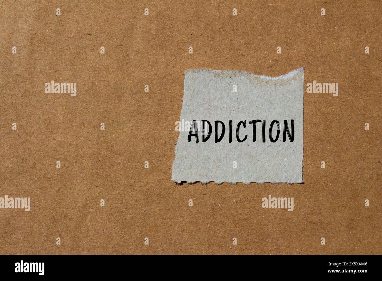 Addiction word written on ripped paper with brown background. Conceptual addiction symbol. Copy space. Stock Photo