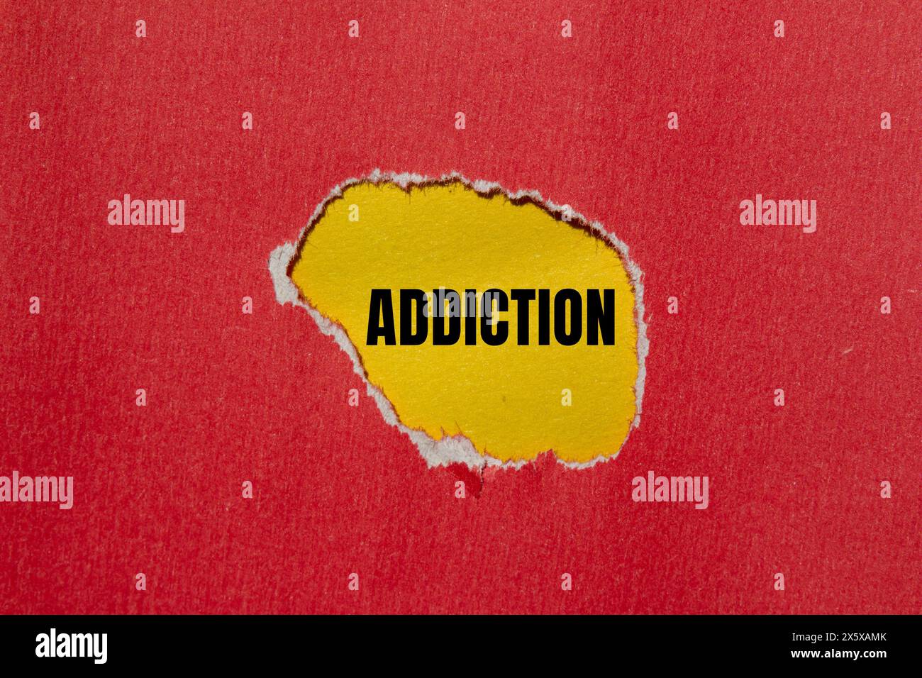 Addiction word written on ripped red paper with yellow background. Conceptual addiction word symbol. Copy space. Stock Photo