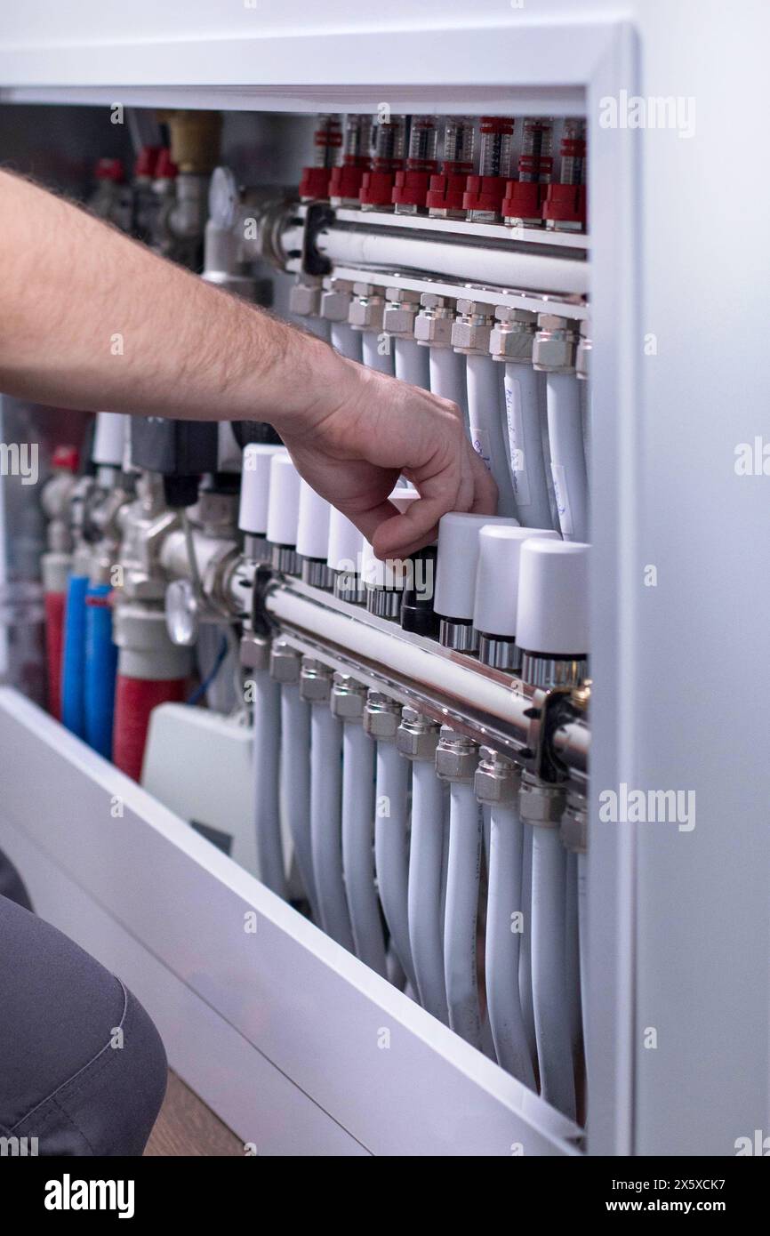 Plumber work. Installing collector for warm water underfloor heating system. Stock Photo
