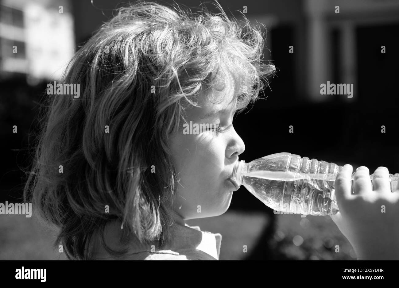Portrait of a cute child boy drinking water from bottle. Close up caucasian kids face. Closeup head of funny kid. Stock Photo