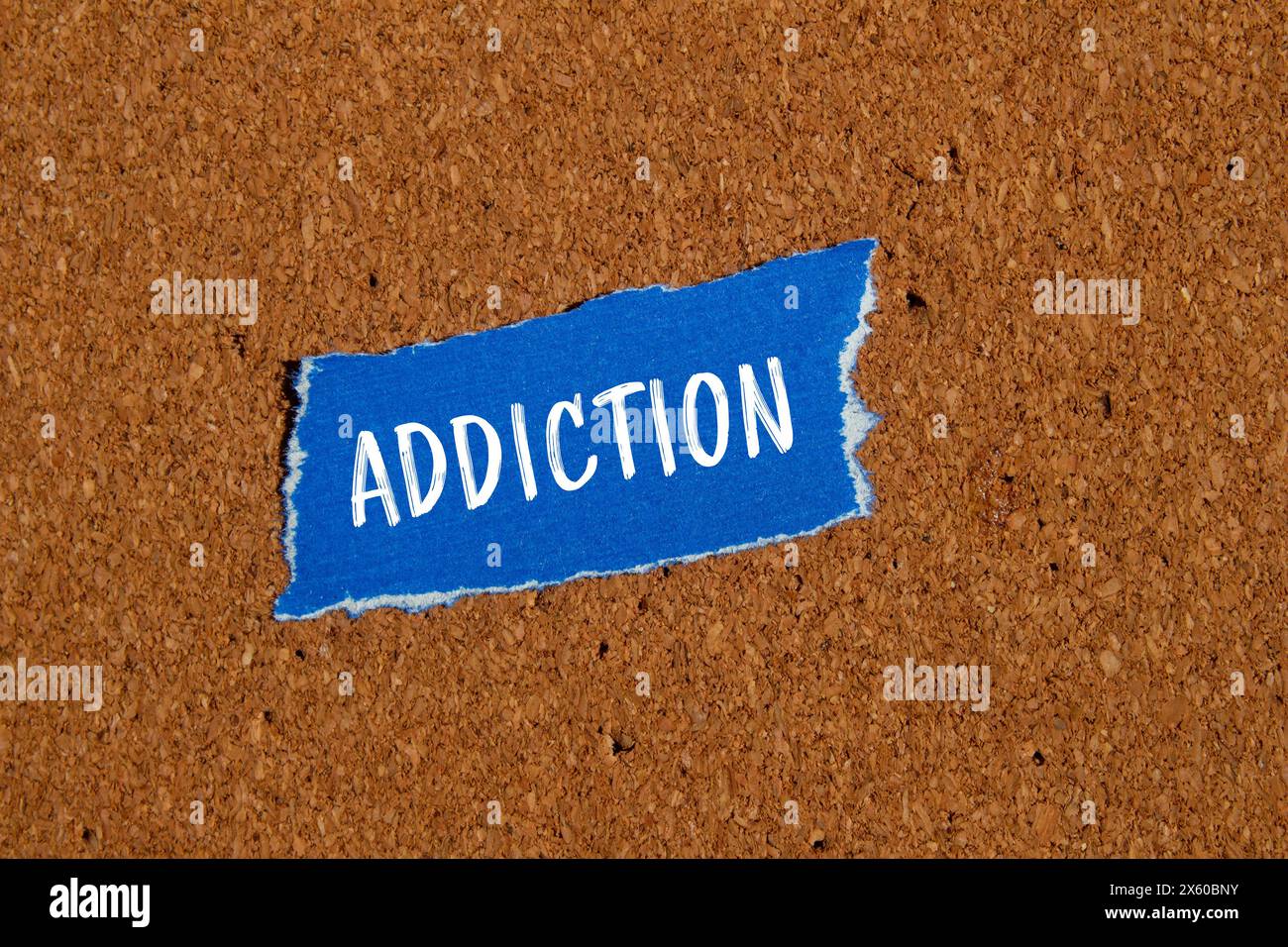 Addiction word written on ripped blue paper piece with brown background. Conceptual addiction symbol. Copy space. Stock Photo