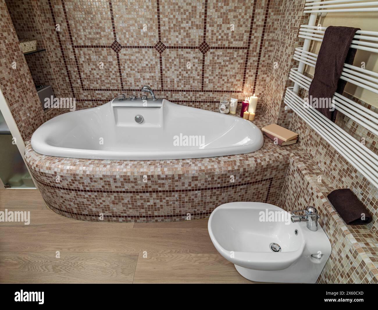 interior view of a modern bathroom, in foreground the bidet in background the bathtub, the walls are coated with mosaic tiles instead the floor is mae Stock Photo