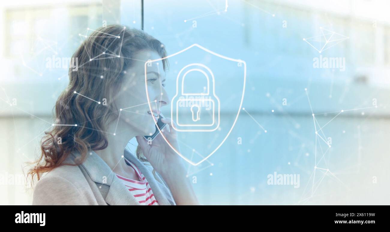 Image of padlock in shield, connected icons over caucasian woman talking on smartphone Stock Photo