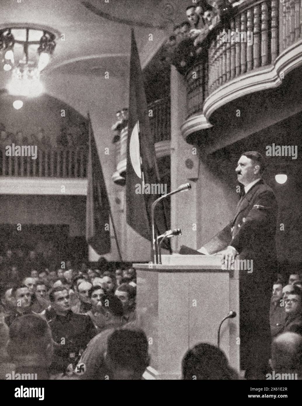 Adolf Hitler, seen here making a speech in the Buergerbraukeller, a beer hall in Munch, minutes before a bomb exploded shattering the building, thereby escaping an assassination attempt by Georg Elser, 8th November, 1939. Adolf Hitler, 1889 – 1945. German politician, demagogue, Pan-German revolutionary, leader of the Nazi Party, Chancellor of Germany, and Führer of Nazi Germany from 1934 to 1945. From The War in Pictures, First Year. Stock Photo