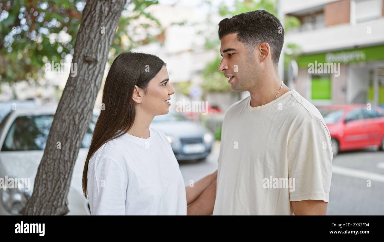 A loving couple stands together on a city street, engaging in a heartwarming conversation. Stock Photo