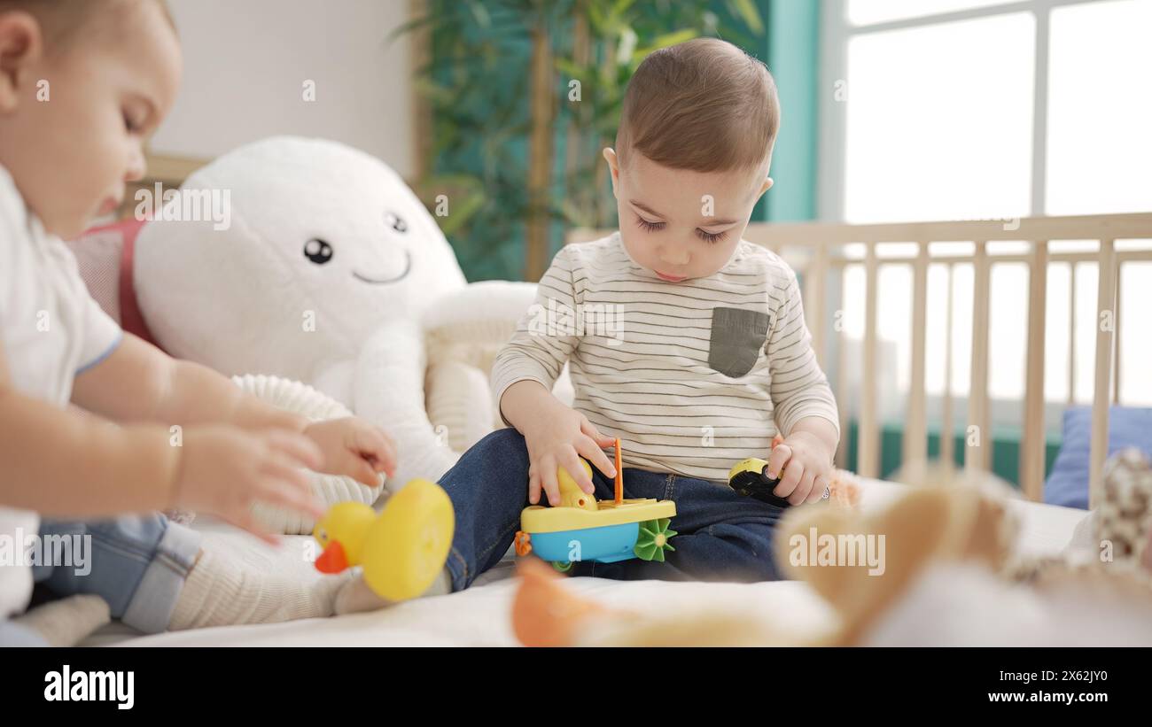 Two adorable toddlers sitting on bed playing at bedroom Stock Photo - Alamy