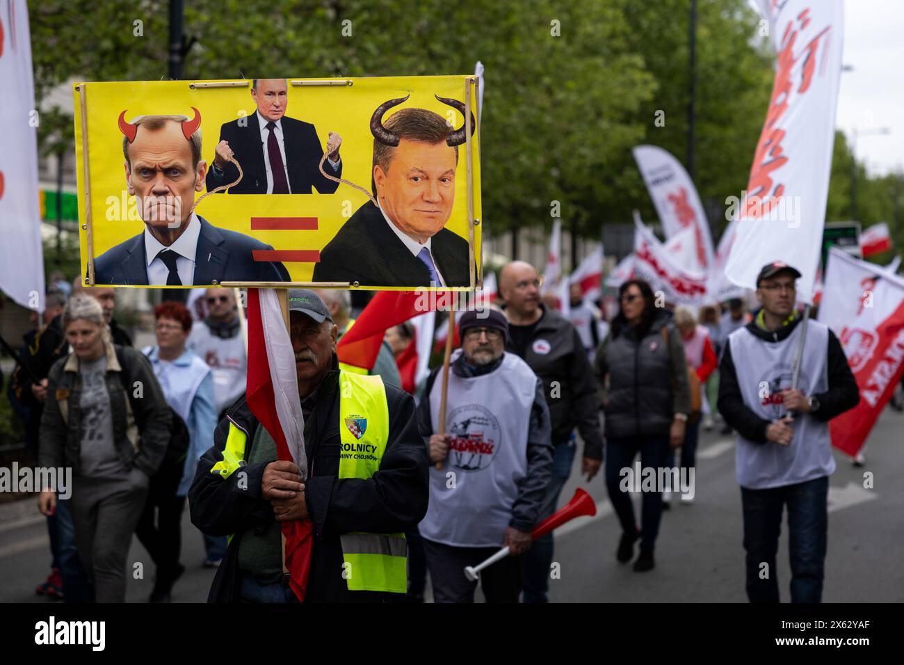 May 10, 2024, Warsaw, Mazovian Province, Poland: A protester holds a banner with images of Russian President Vladimir Putin, Polish Prime Minister Donald Tusk and former Ukrainian president Viktor Yanukovych, comparing the latter two to each other, during a protest against the European Union's Green Deal ahead of EU parliamentary elections, in Warsaw. The protest was organized by the Independent Self-Governing Trade Union ''Solidarity'', farmers, right-wing and anti-EU movements with the participation of Law and Justice and Confederation politicians. (Credit Image: © Maciek Jazwiecki/ZUMA Pres Stock Photo