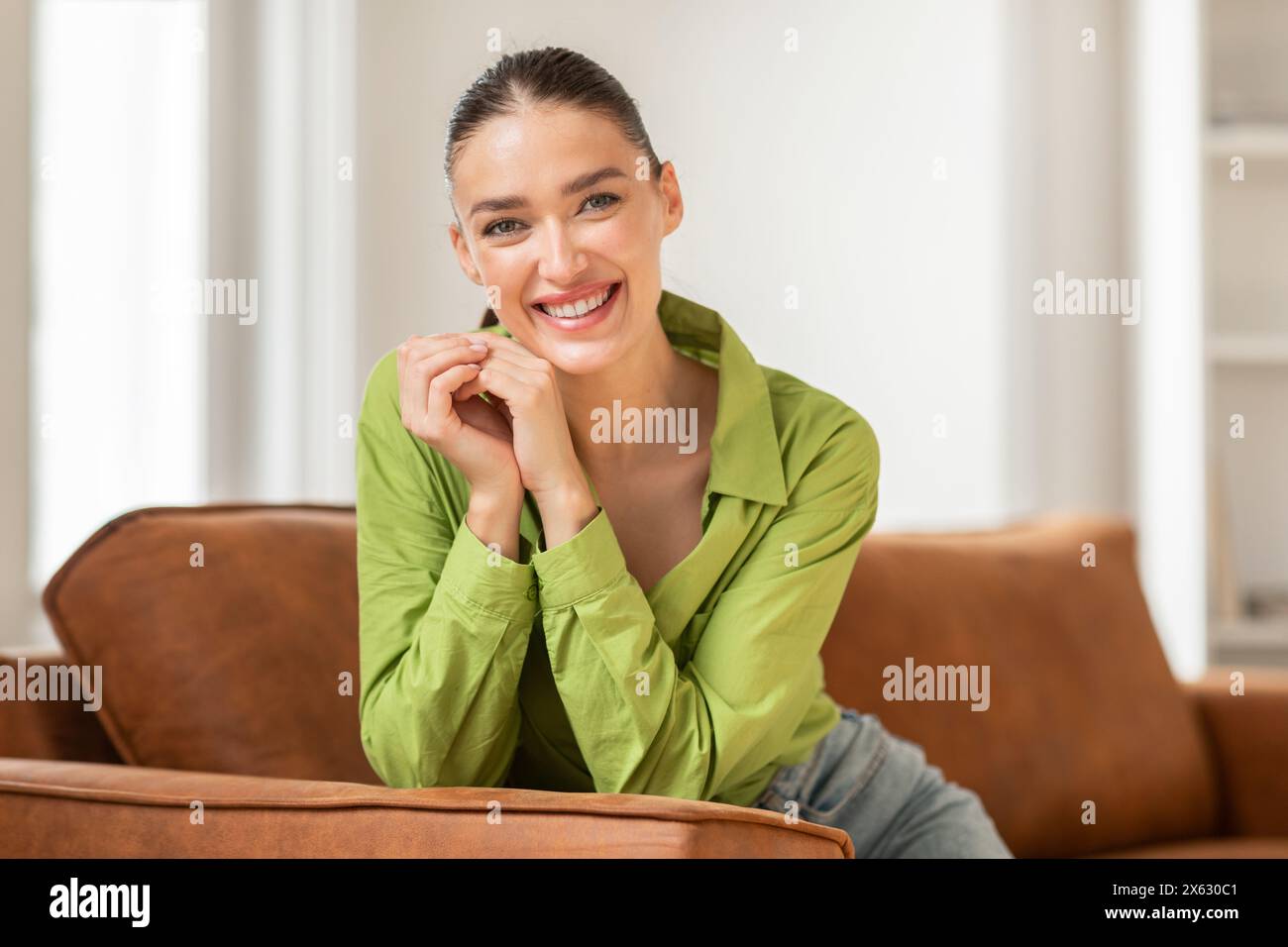 Smiling Woman Sitting on Couch at Home Stock Photo