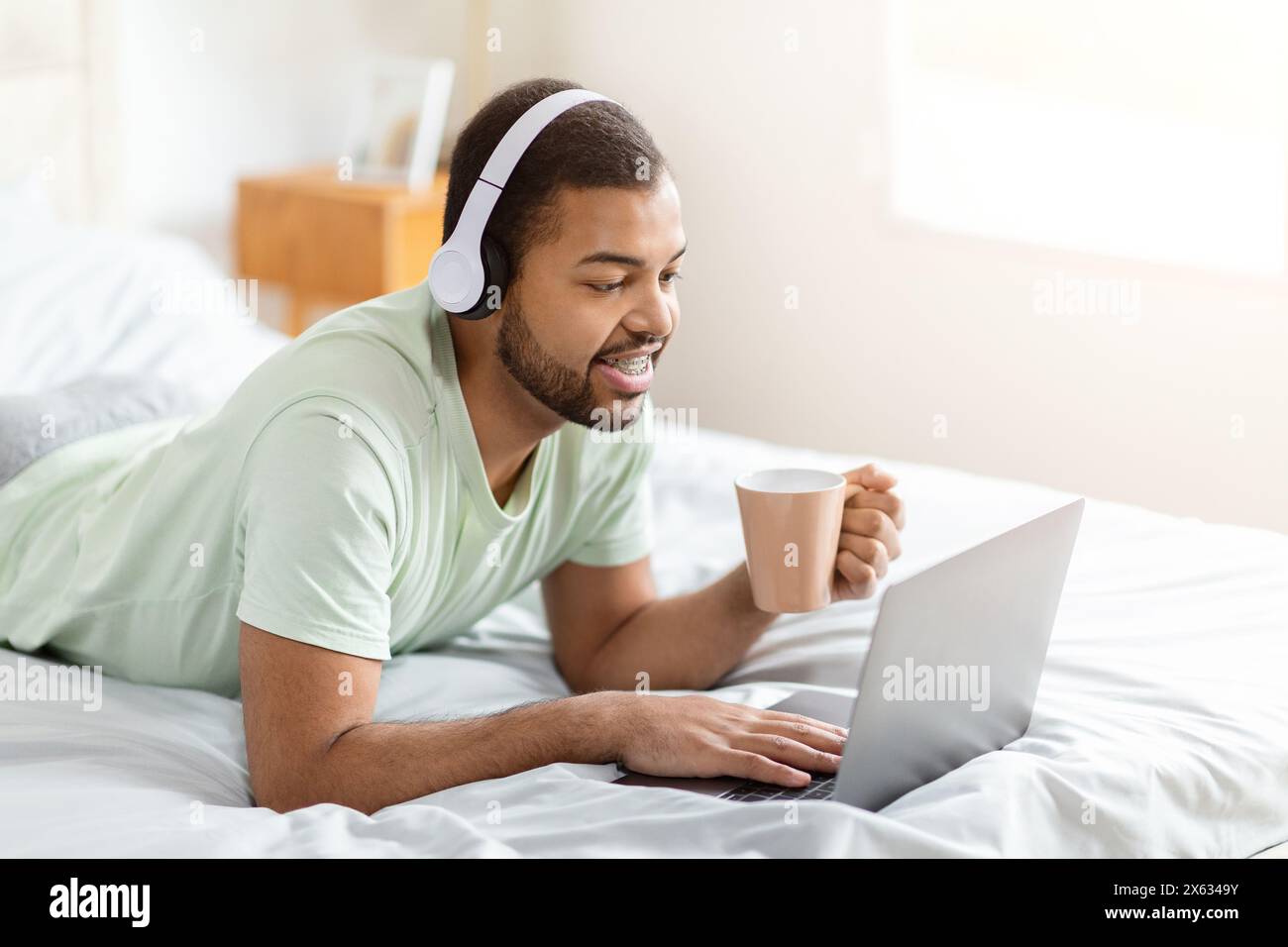Man With Laptop and Coffee on Bed Stock Photo