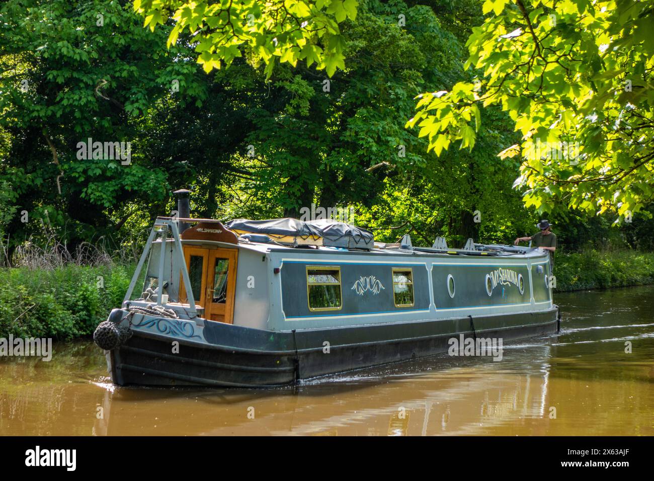 Person  man on canal narrowboat passing through the Shropshire countryside on the Shropshire union canal near the town of Market Drayton England UK Stock Photo