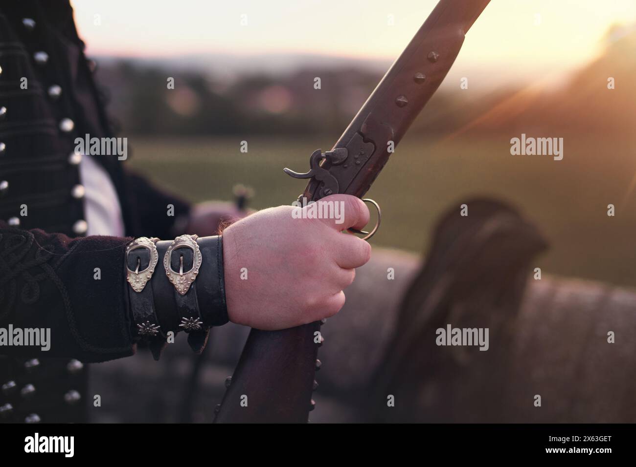 Outlaw man hand holding shotgun in sunset closeup Stock Photo