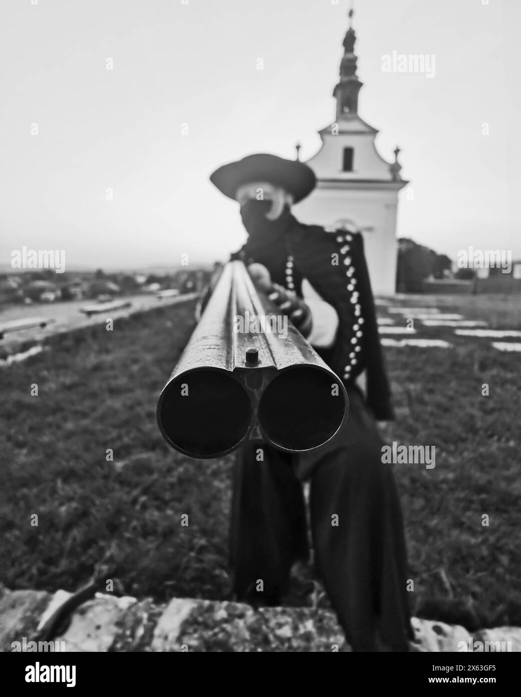 Hungarian outlaw betyar holding shotgun at church, black and white Stock Photo