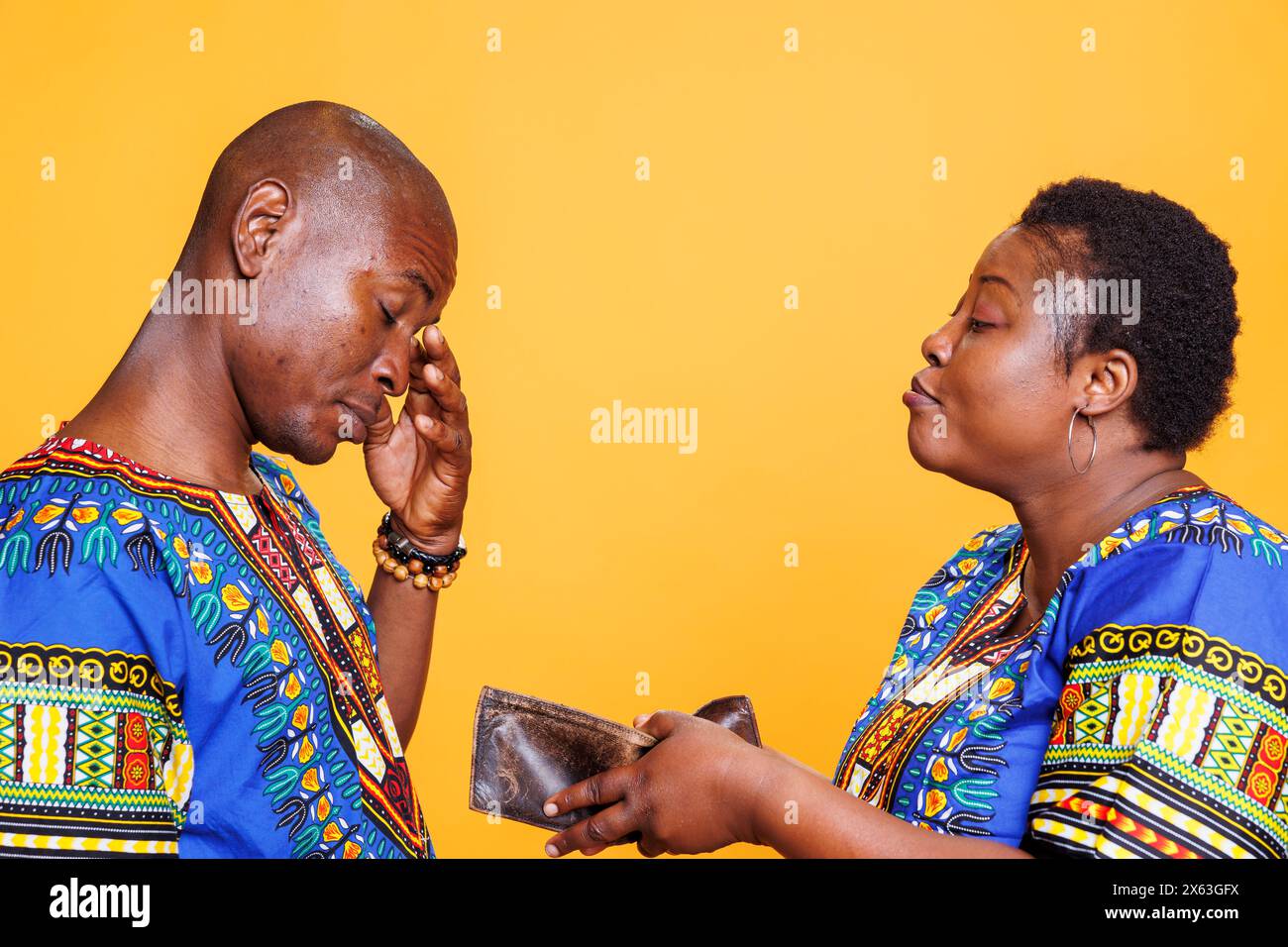 Angry wife showing empty wallet with no money to upset frustrated husband. African american man and woman couple with financial crisis having argument and relationship problem Stock Photo
