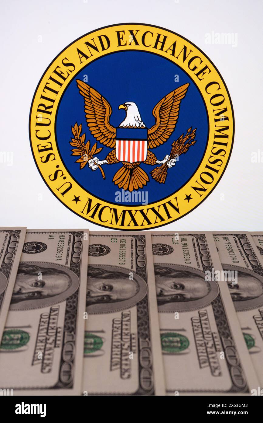 US Securities and Exchange Commision logo seen on the screen and US dollar banknotes in front of it. Stafford, United Kingdom, April 28, 2024 Stock Photo