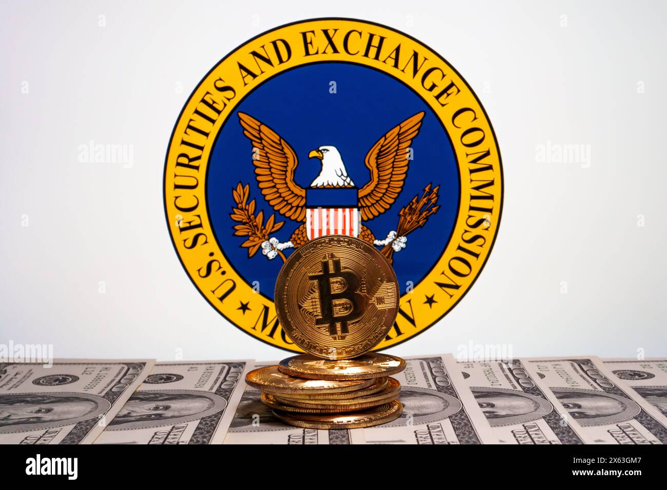 US Securities and Exchange Commision logo seen on the screen and bitcoin with US dollar banknotes in front of it. Stafford, United Kingdom, April 28, Stock Photo