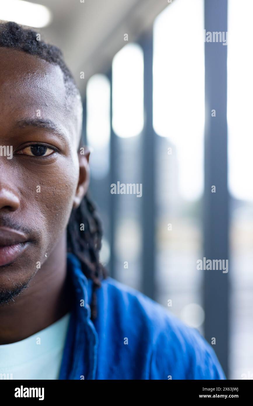 In modern office, a young African American man with braided hair standing, copy space Stock Photo