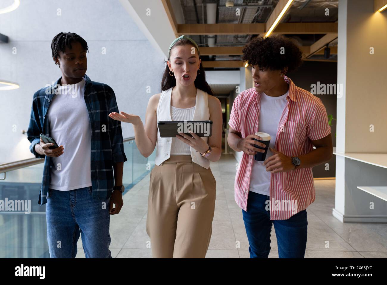 In modern office, diverse young team walking and talking Stock Photo