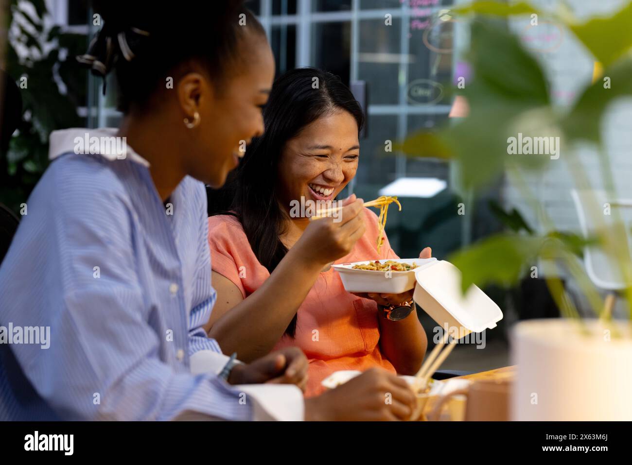 At office, diverse female business colleagues enjoying meal together, working late Stock Photo