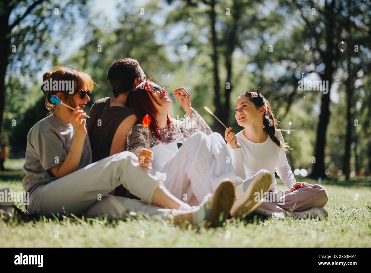 Friends enjoying a sunny day in the park with lollipops and joy Stock ...