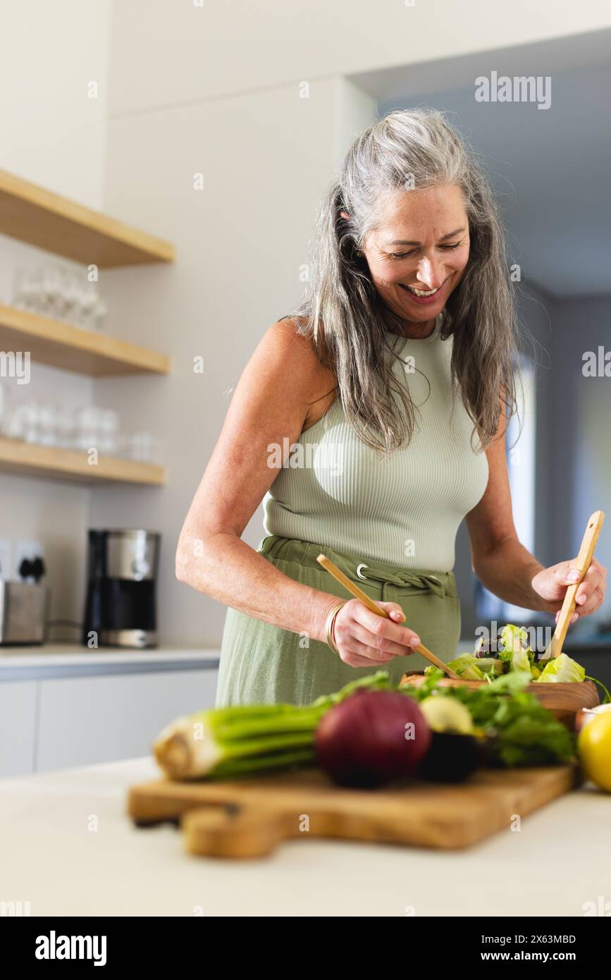 At home, mature Caucasian woman wearing sleeveless top, preparing food Stock Photo