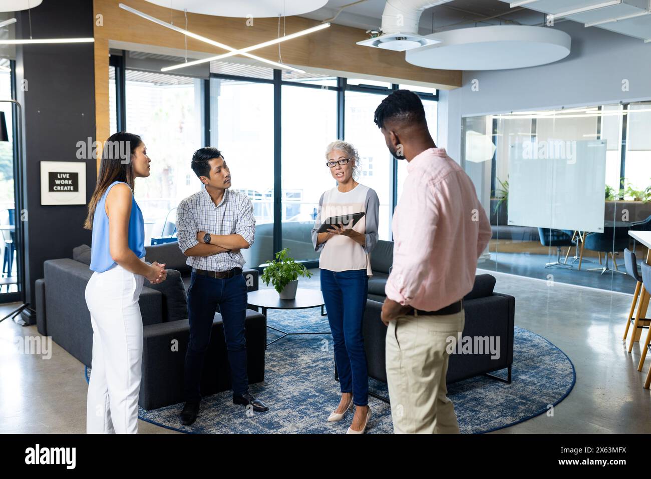 Diverse team discussing at office, holding tablets and notebooks Stock Photo