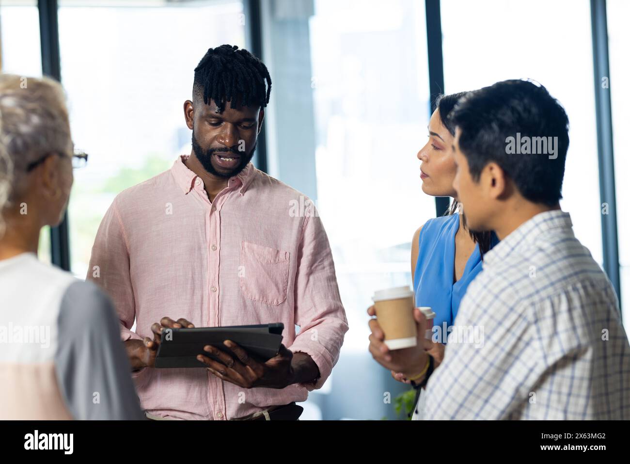 At office, diverse team discussing work using tablet Stock Photo