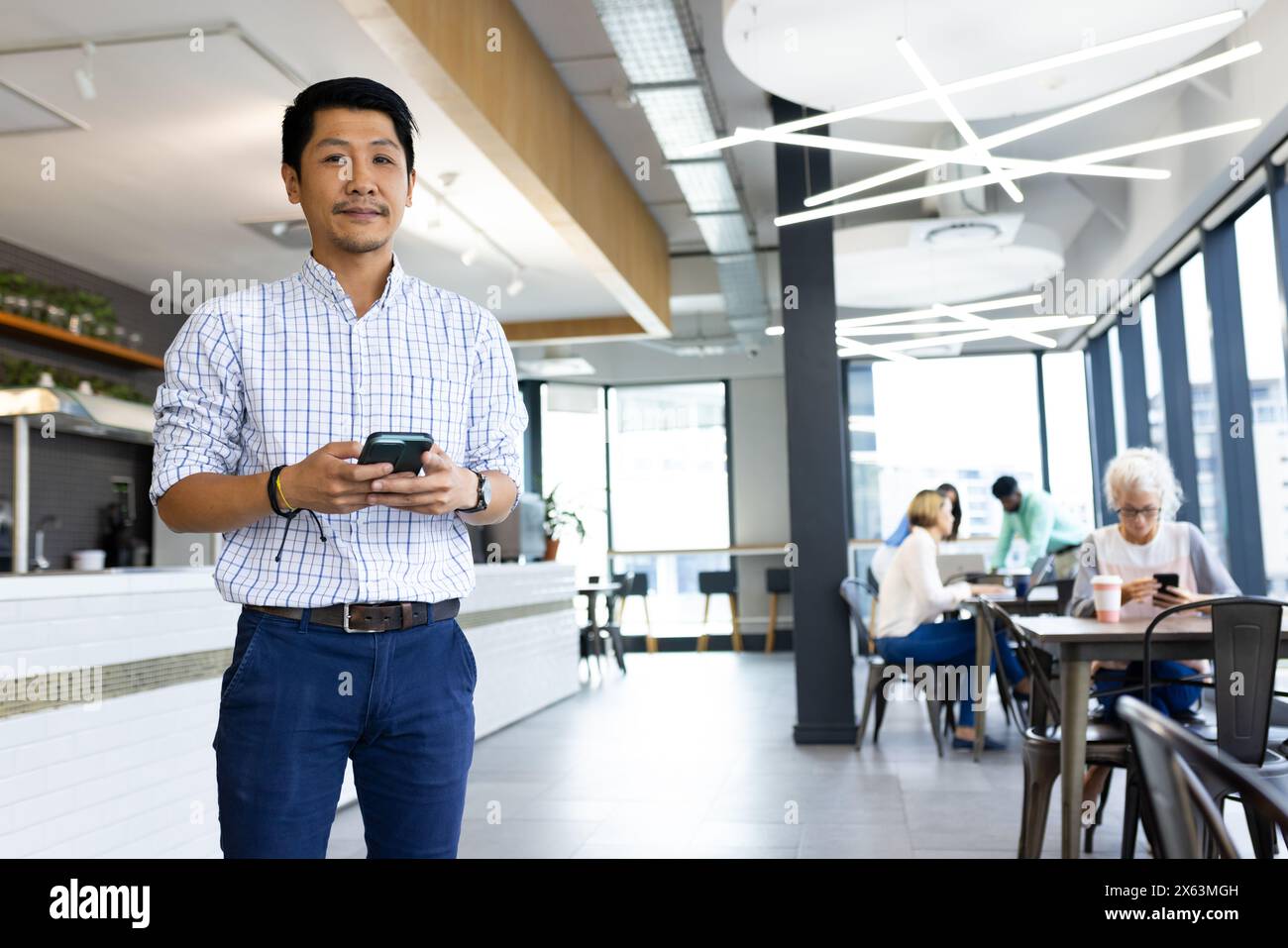Diverse team working at office, Asian male holding smartphone Stock Photo