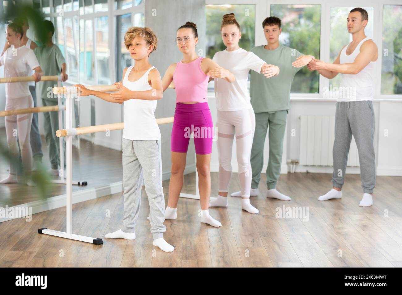 Teenage boys and girls practicing second position of ballet in ...