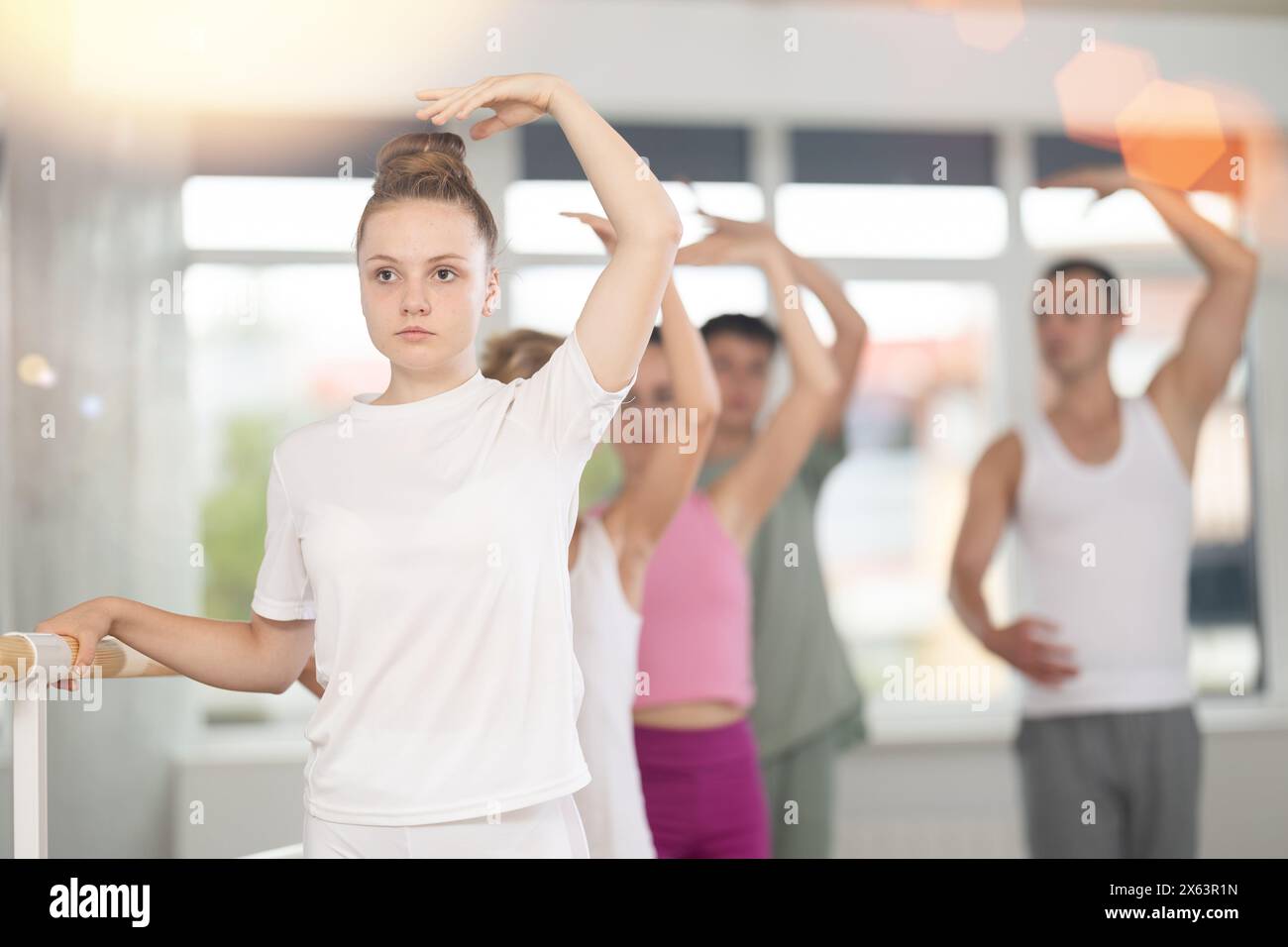 Girl during group class perform third position under male teacher ...