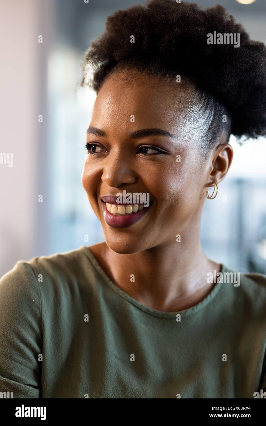 At office, African American businesswoman wearing green top, looking away Stock Photo