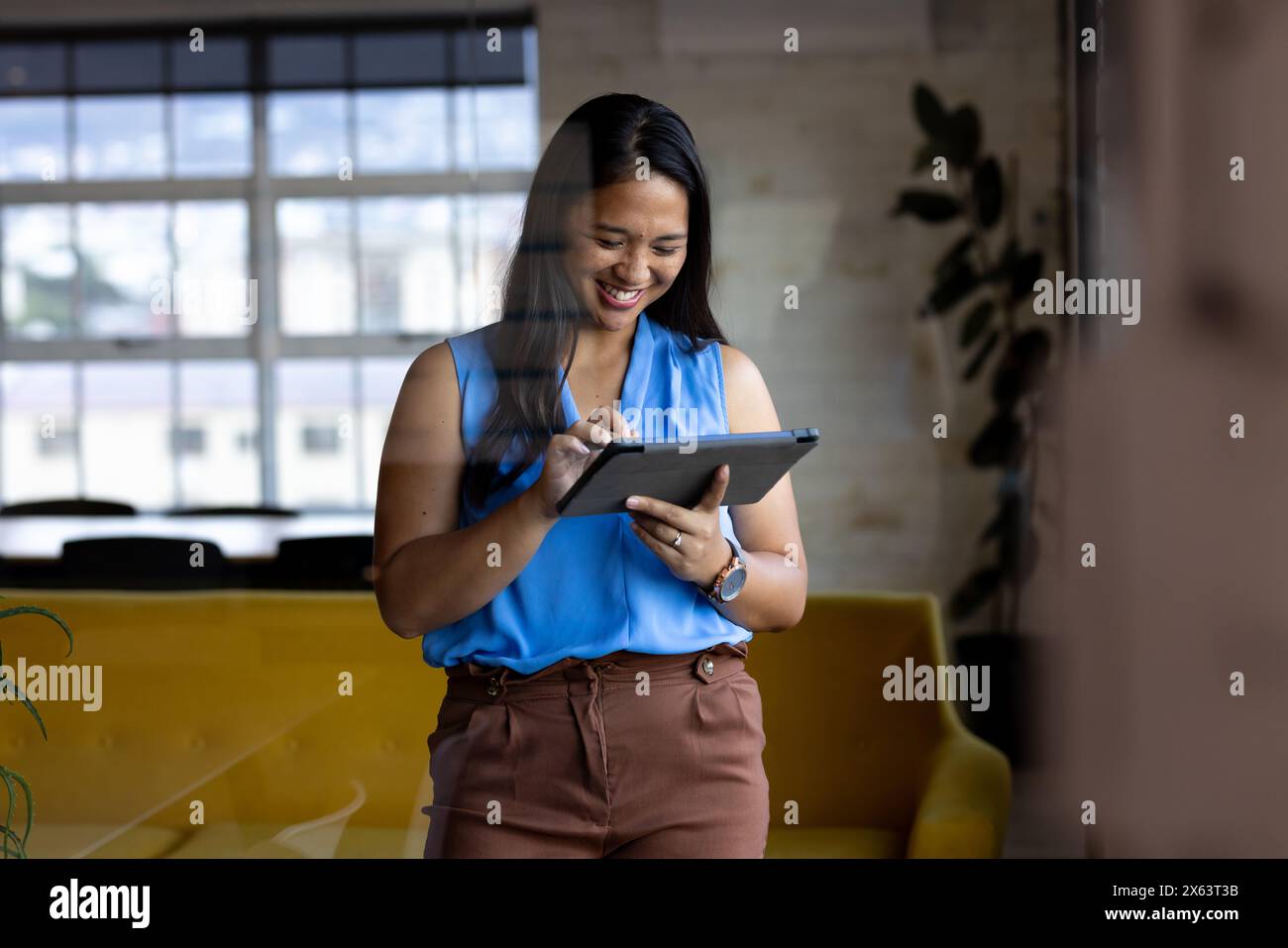 At office, biracial businesswoman using tablet, standing Stock Photo