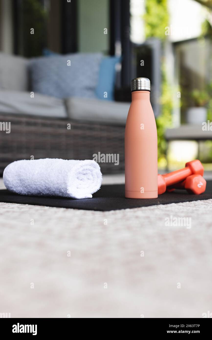 At home: white towel, peach bottle, red dumbbells on mat Stock Photo