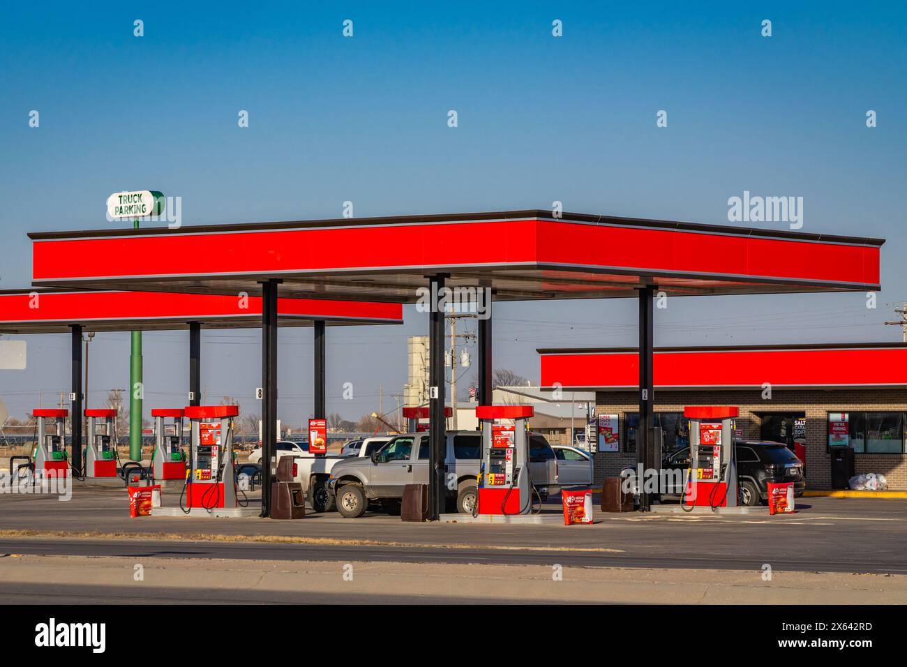 Gas station with bright red overhead roof on sunny day and cars and