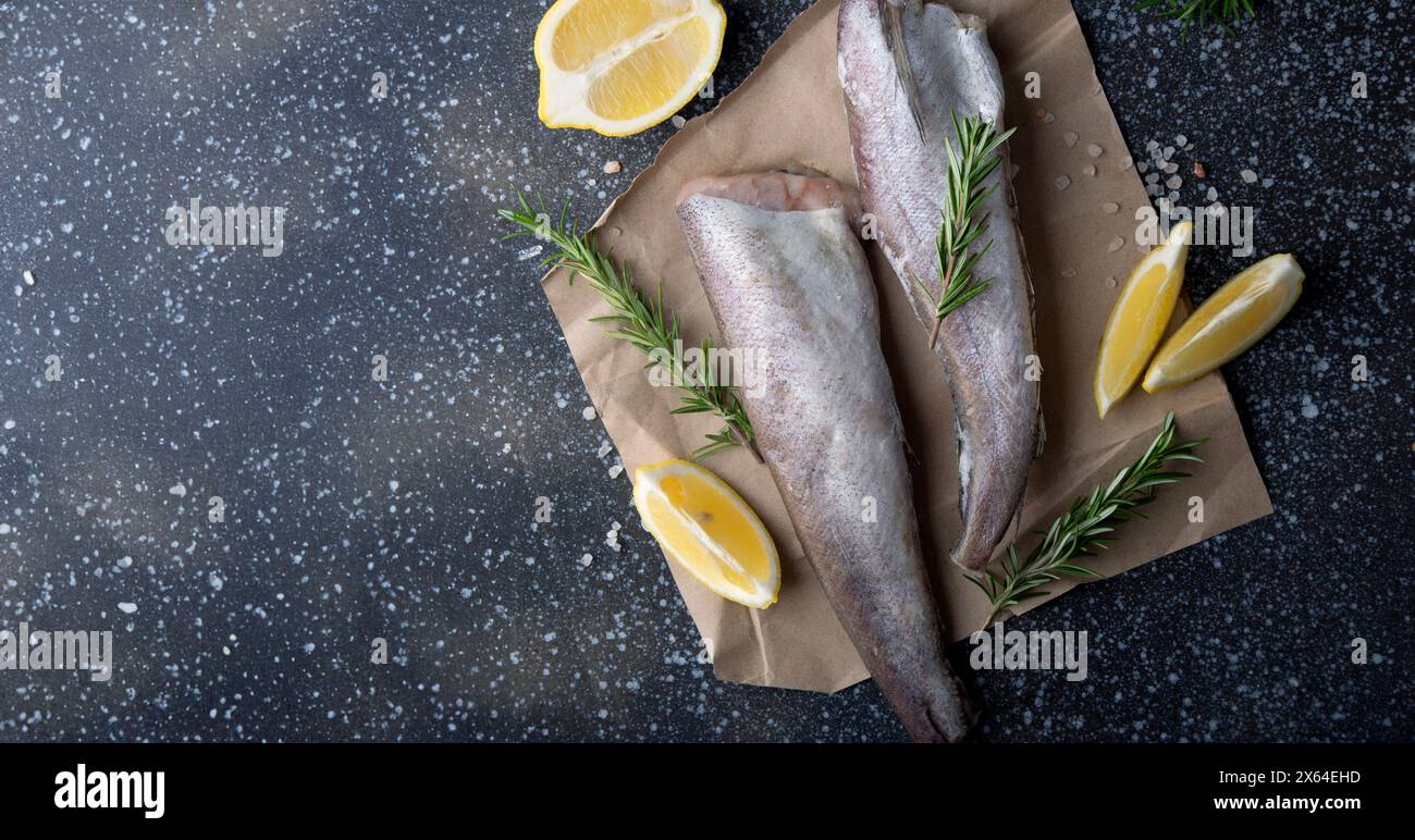 Culinary presentation of uncooked hake with aromatic herbs, suited for gourmet cooking tutorials or menu imagery. Extra wide banner Stock Photo
