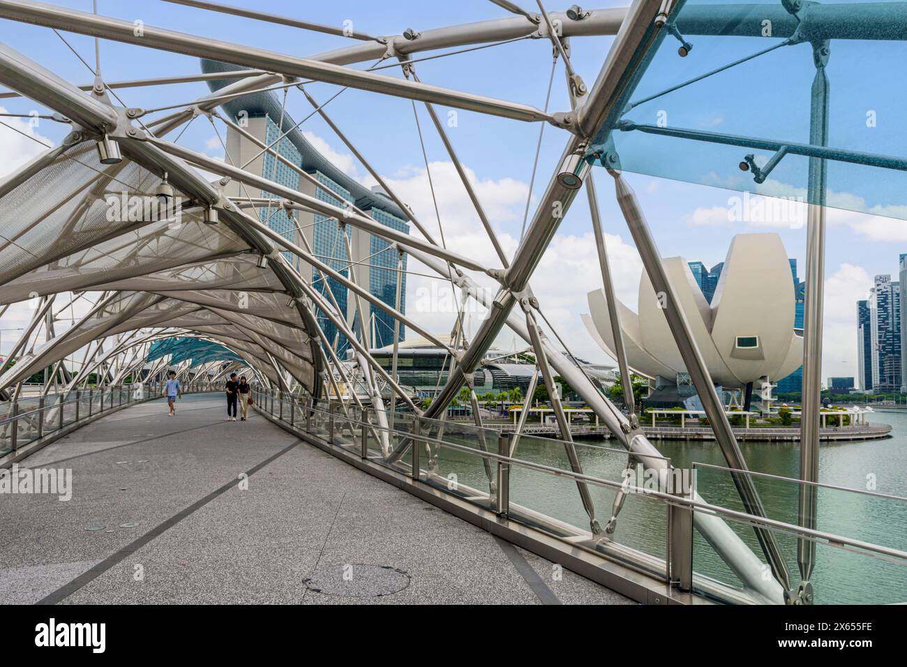 The complex twisted steel of the pedestrian Helix Bridge with views over to the Marina Bay Sands and ArtScience Museum, Marina Bay, Singapore Stock Photo