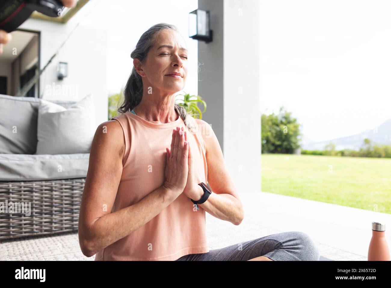 At home, Caucasian mature woman practicing yoga outside Stock Photo